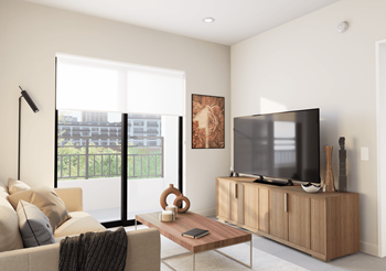 Living room with a couch, coffee table and TV, with bright natural light entering through the sliding glass door at Hollywood Heights on the Boulevard in Hollywood, FL
